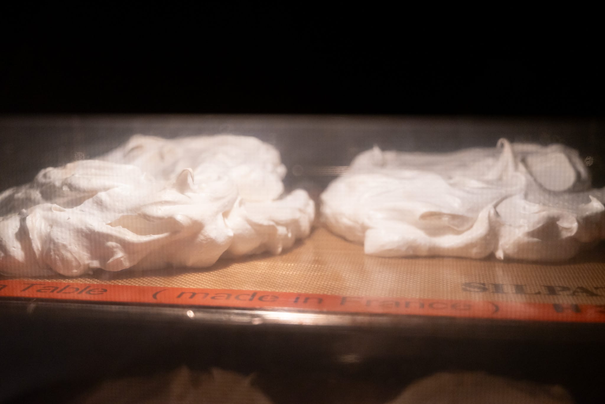 Meringues baking seen through an oven door